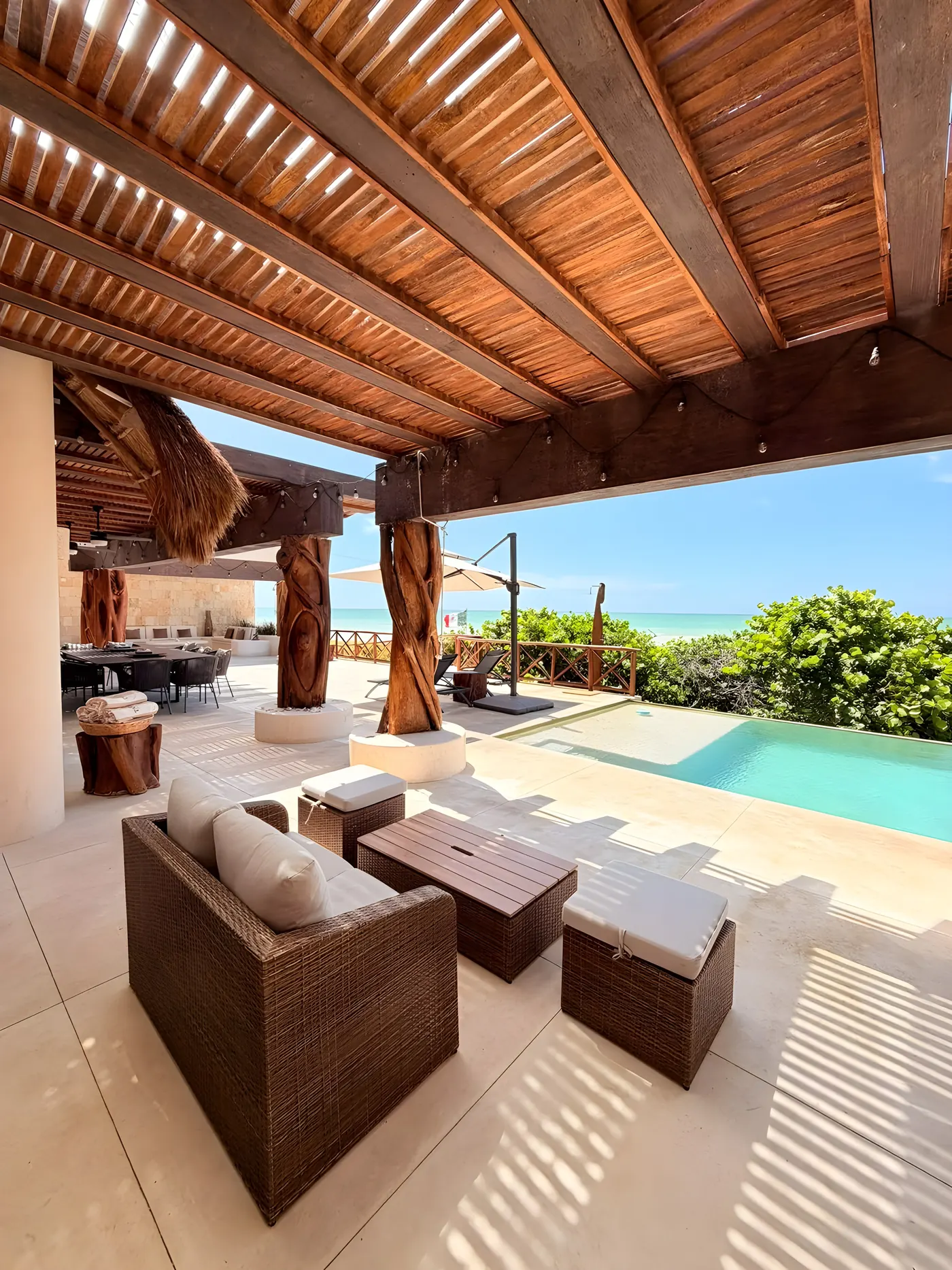 Sala exterior de Casa María bajo la pérgola, junto a la alberca y frente al mar